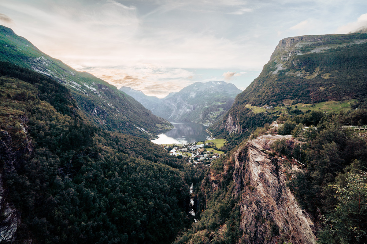 Valley with a fjord and small village, surrounded by tall green mountains
