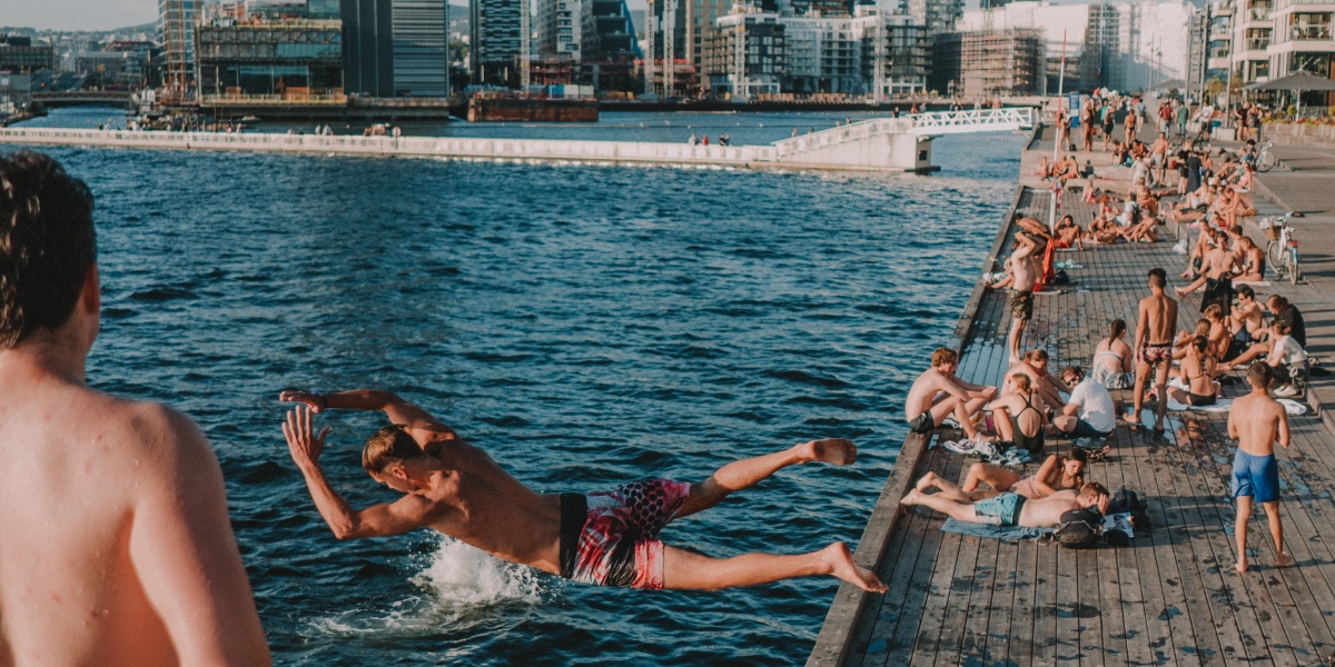 A man in swimming trunks jumping into the sea from a wooden pier.